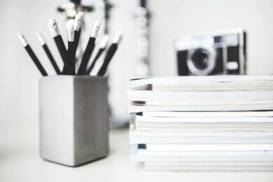 A pencil pot, papers and a camera